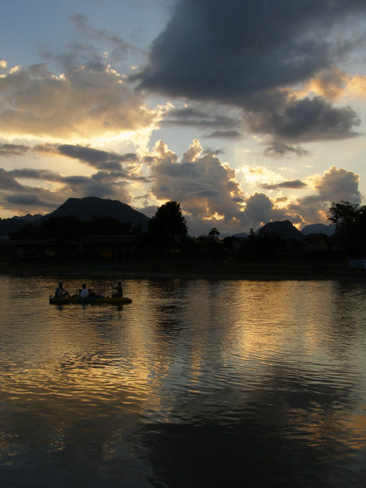 Tourists on the river in front of a Vang Vieng sunset